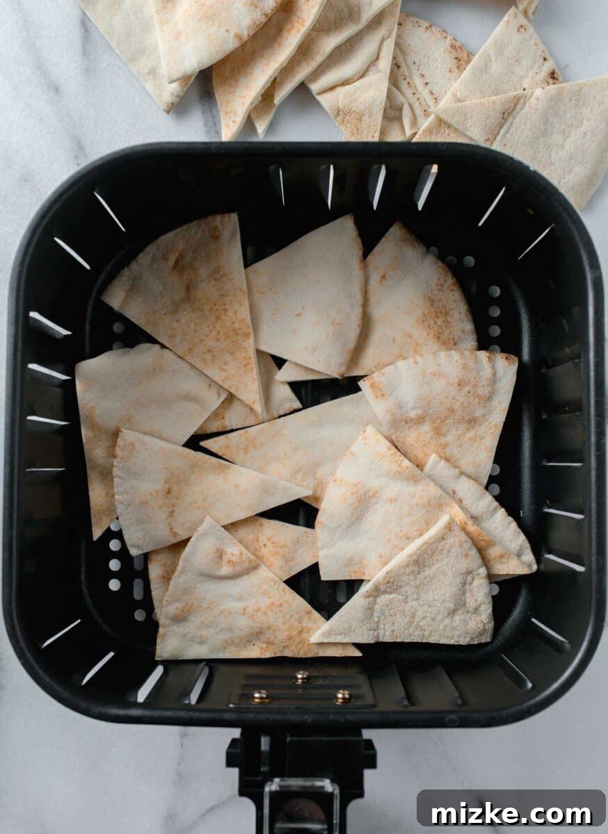 Crispy Air Fryer Pita Chips 5 Perfectly sliced pita bread triangles carefully arranged in the basket of an air fryer, awaiting their transformation into crispy chips.