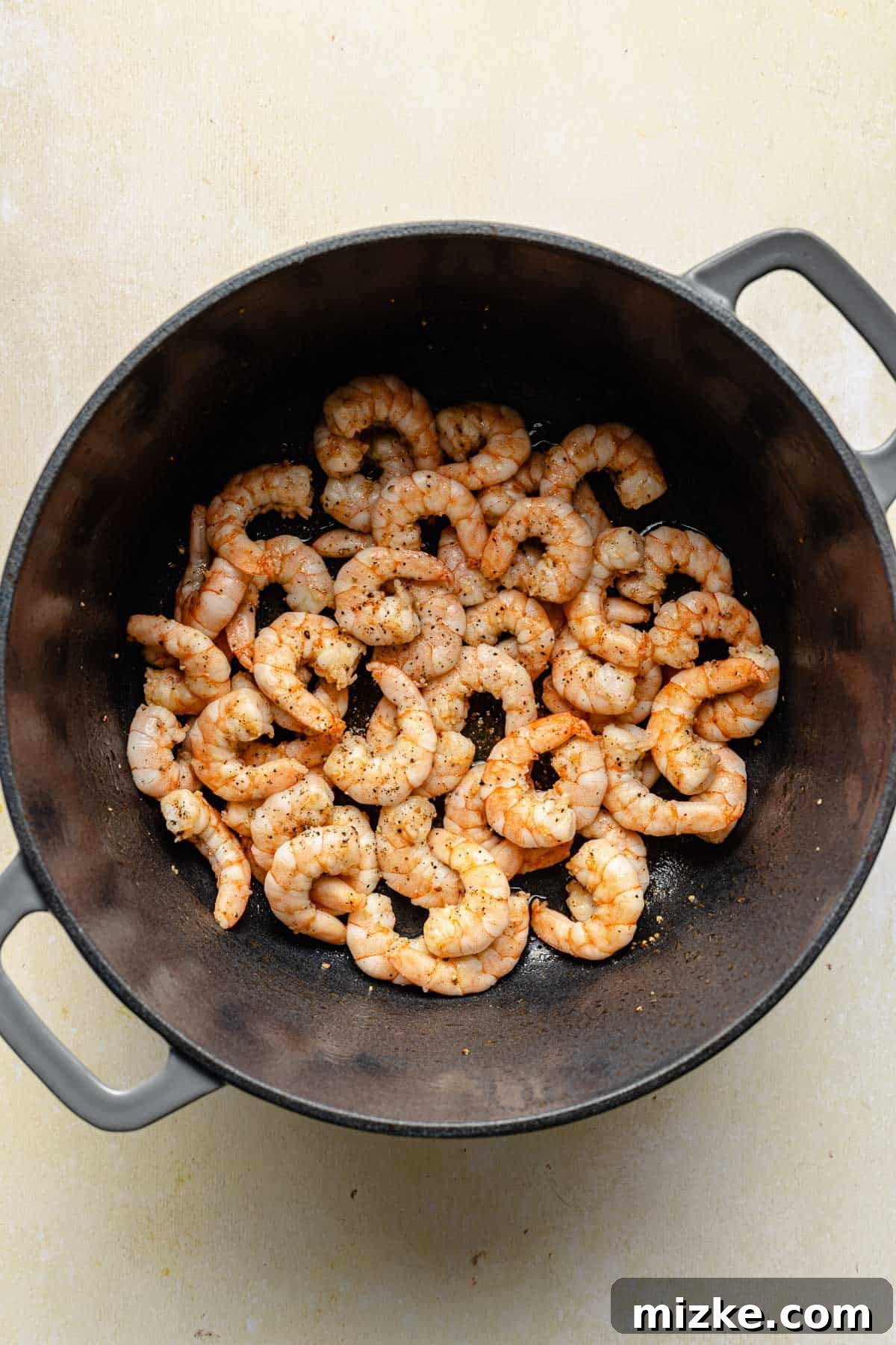Sautéing shrimp for easy shrimp risotto. Cooking seasoned shrimp in a large Dutch oven until opaque.