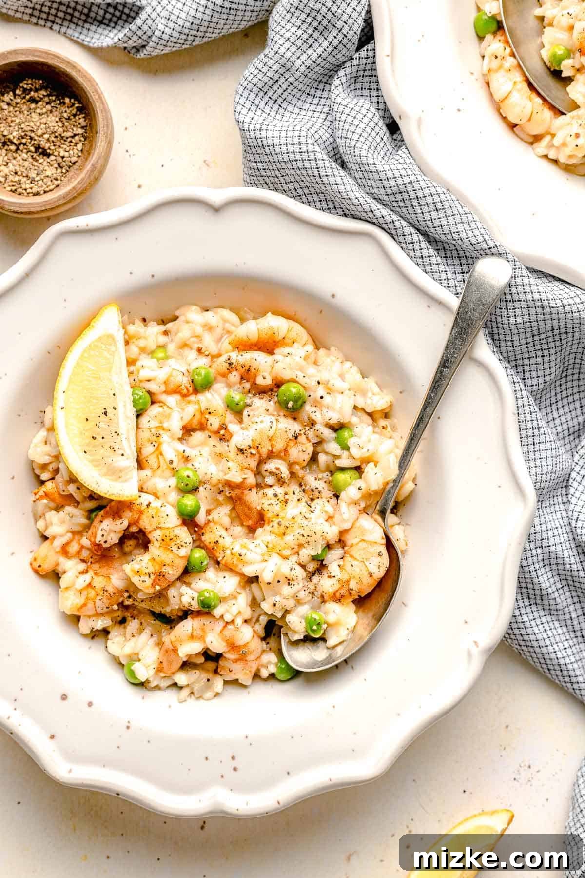 A perfect serving of easy shrimp risotto ready to be enjoyed. Overhead view of shrimp risotto served in a single bowl with a spoon, highlighting its creamy texture.