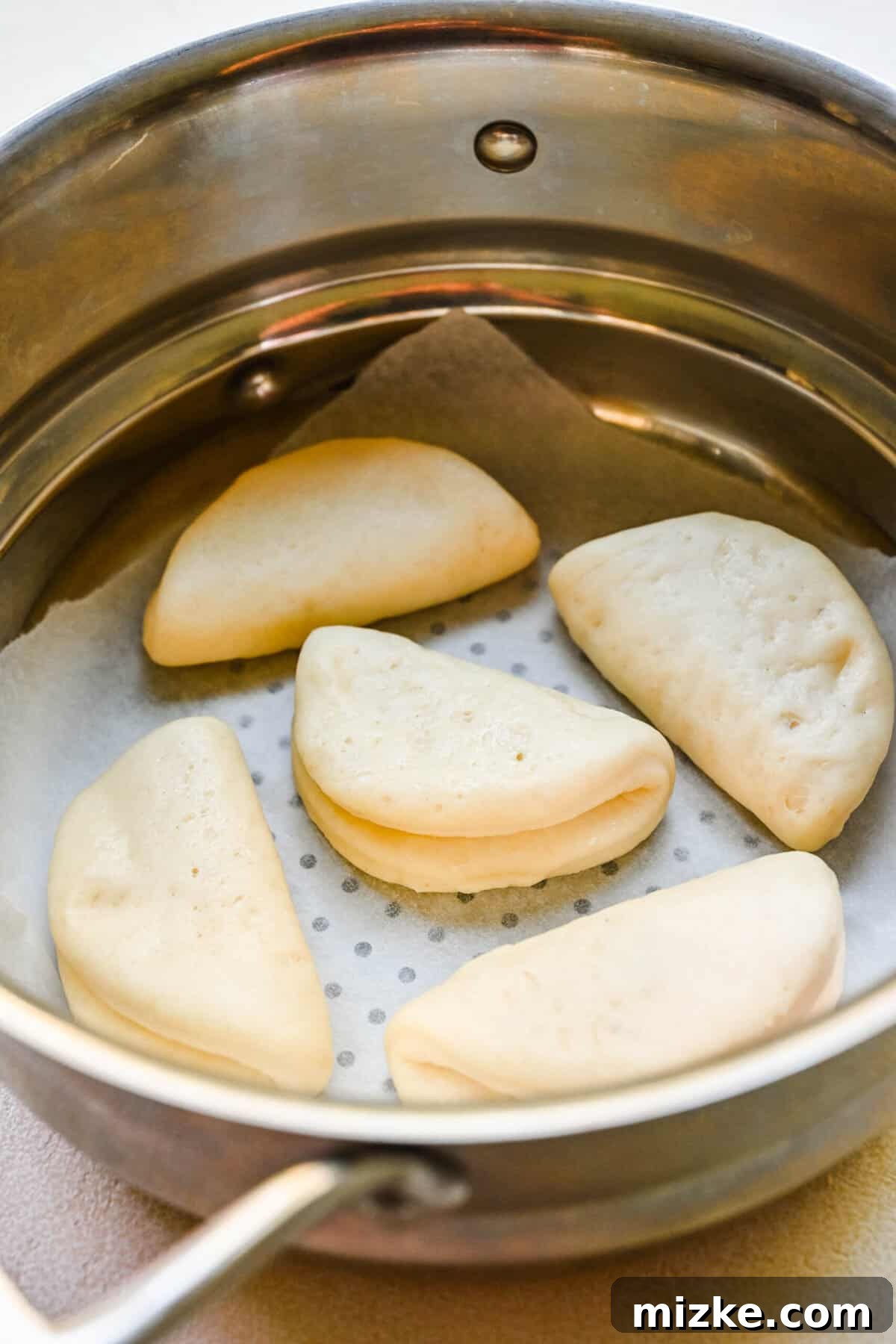 Bao buns arranged in a bamboo steamer basket for cooking