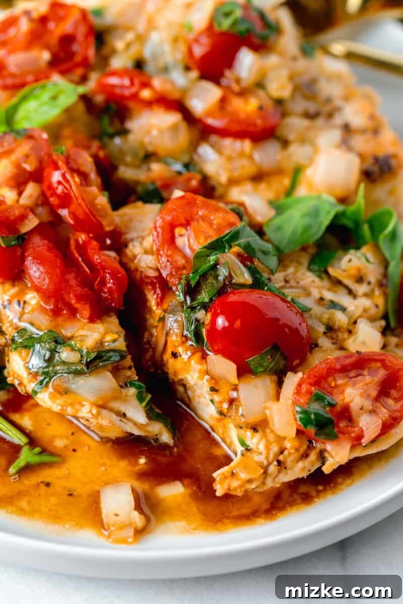 Skillet Roasted Garlic Tomato Basil Chicken 6 chicken breast sliced in half with grape tomatoes and basil and onions on top with balsamic vinegar around the sliced chicken