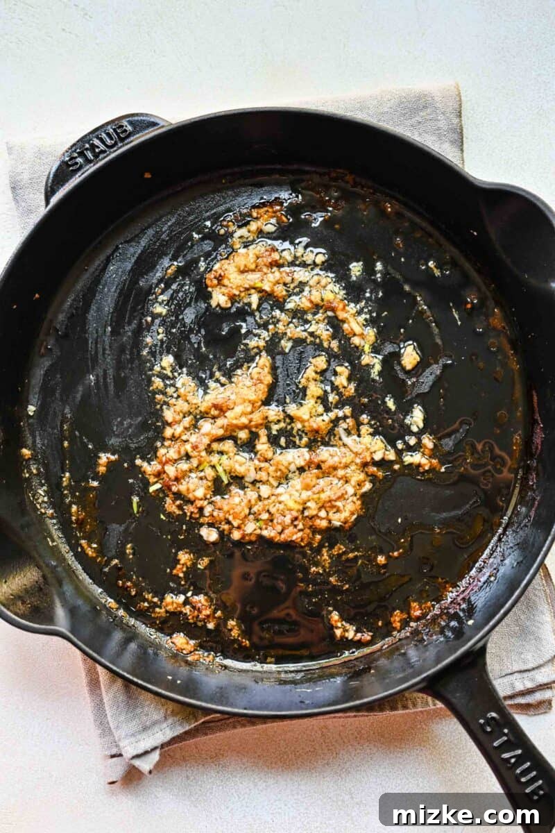 Step 5: Beginning the stir-fry by sautéing aromatic garlic and ginger. Sautéing minced garlic and grated ginger in a pan, creating an aromatic base.