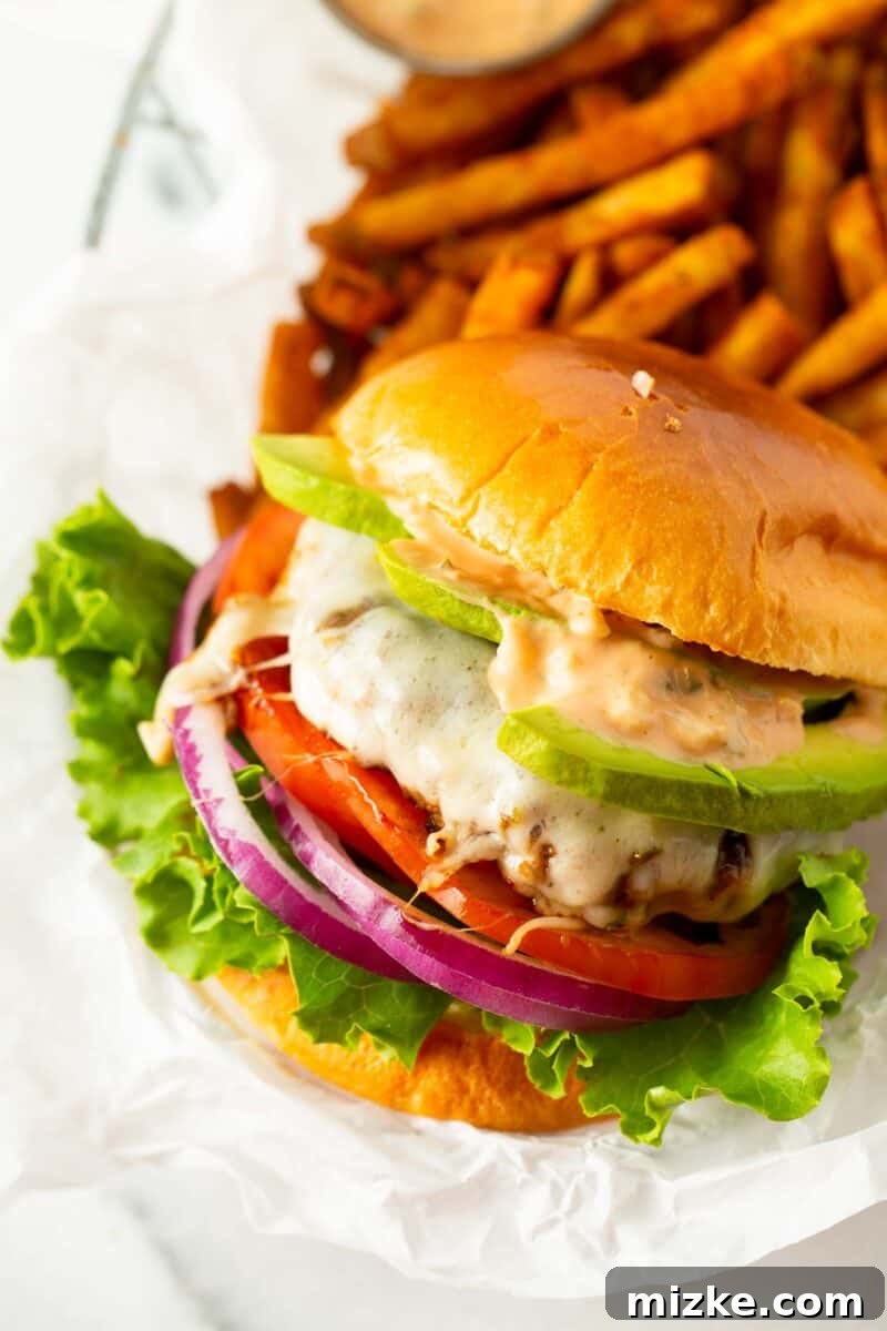 Golden State Delight 2 california burger on white parchment paper next to fries