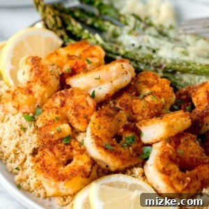 lemon pepper shrimp on a bed of couscous with fresh lemon slices and sprinkled fresh parsley on top