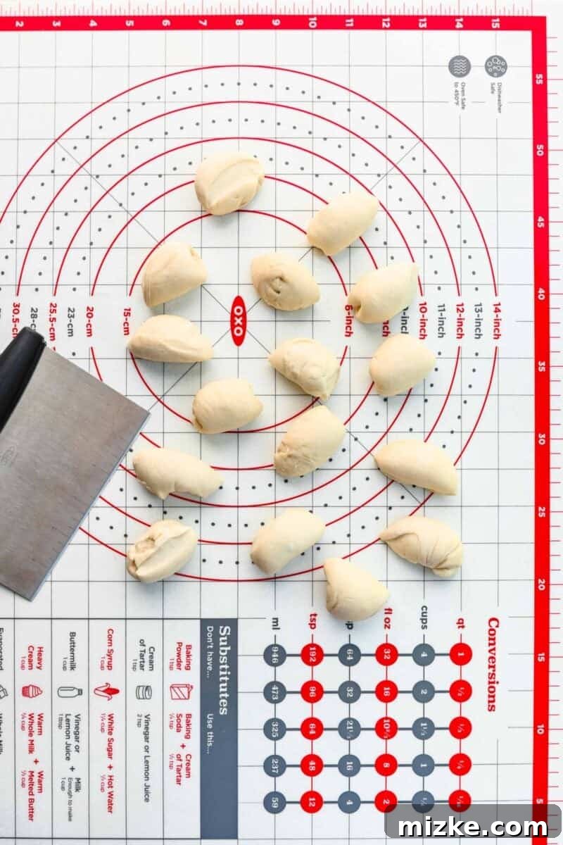 Dividing pizza dough into 16 portions for making consistent pizza bites. Pizza dough being divided into 16 equal portions on a lightly floured surface, ready for shaping.