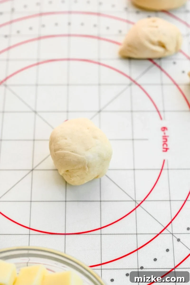 A close-up of a sealed pizza ball, ready to be placed in the skillet. Close-up shot of a perfectly sealed pizza ball, showing the pinched seam, ready for baking.