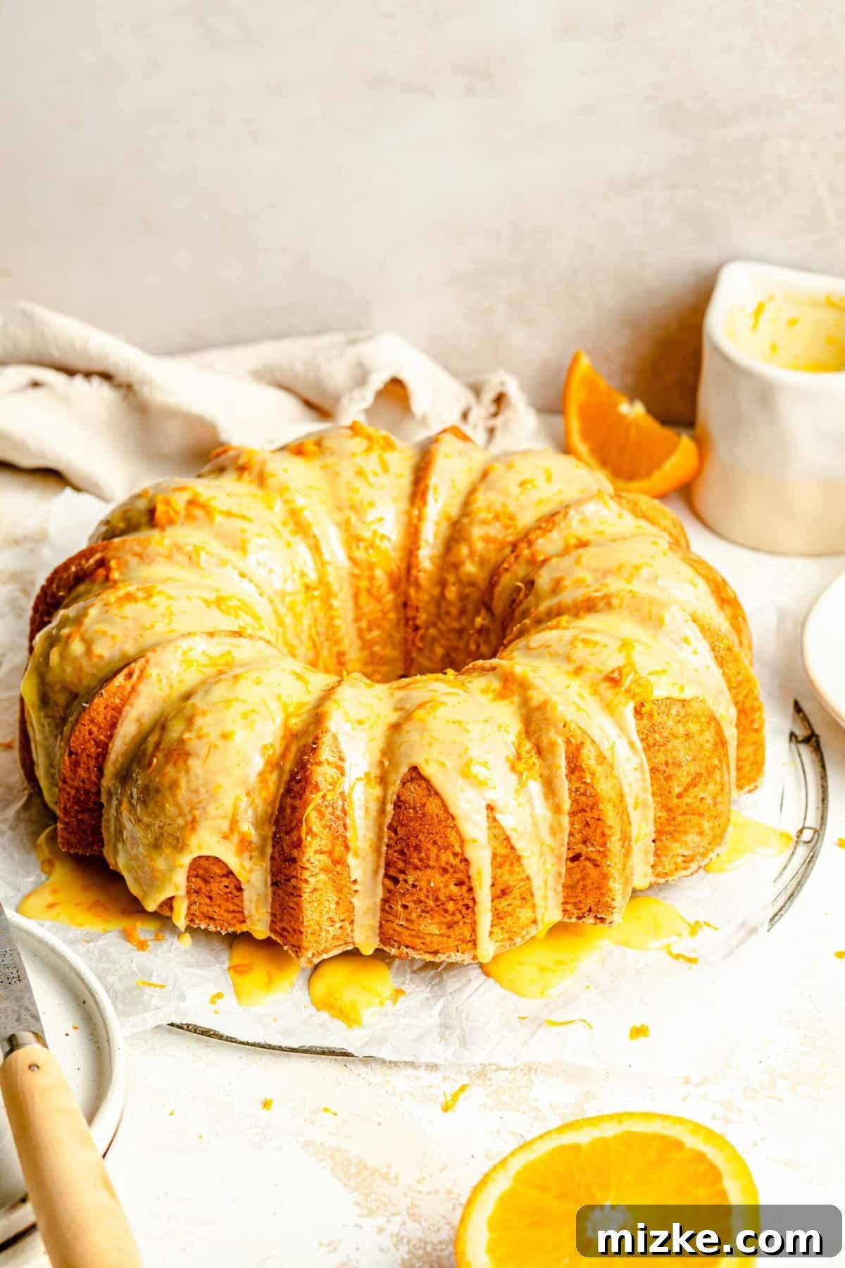 Experience the delightful blend of tender, buttery orange pound cake and its sweet, fresh orange glaze, creating a dessert loaded with real citrus flavor. A beautifully baked orange pound cake with a generous orange glaze cascading down its sides, ready to be sliced and served.