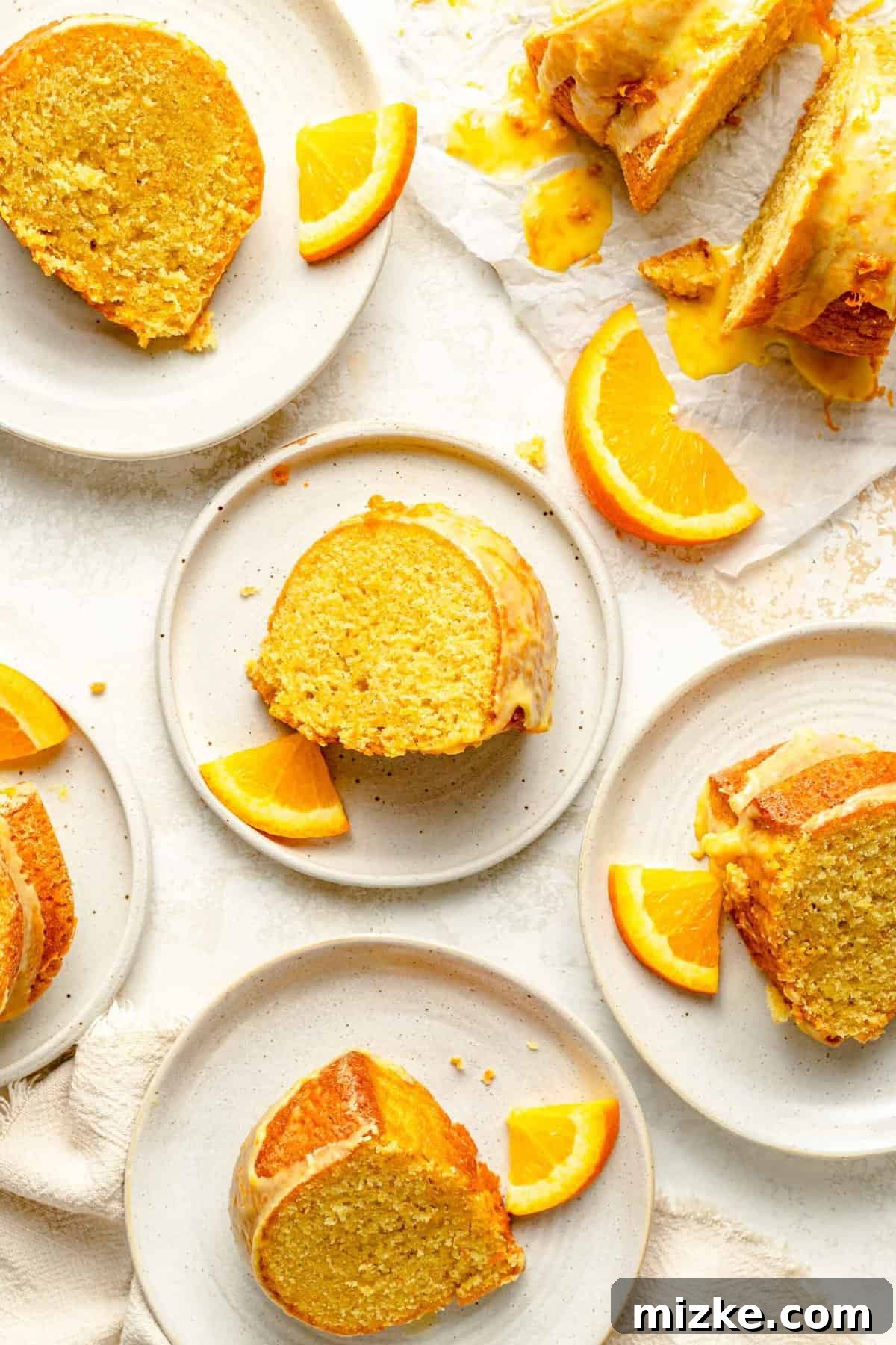 Serve delightful slices of orange pound cake, each one a testament to its tender, buttery texture and sweet orange glaze, perfect for any gathering. Perfectly cut slices of glazed orange pound cake elegantly arranged on individual white plates, garnished with fresh orange zest, ready to be enjoyed.