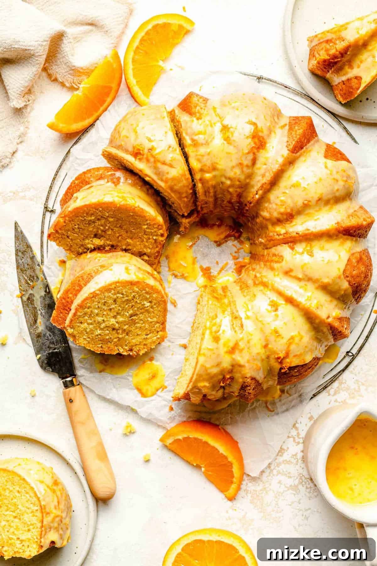 An exquisite overhead shot of the tender, buttery orange pound cake, glistening with its sweet orange glaze, truly loaded with real citrus flavor and ready to be enjoyed. An inviting overhead view of the full orange pound cake, beautifully glazed, with a few slices already removed, showcasing its delicious, moist interior and golden crust.