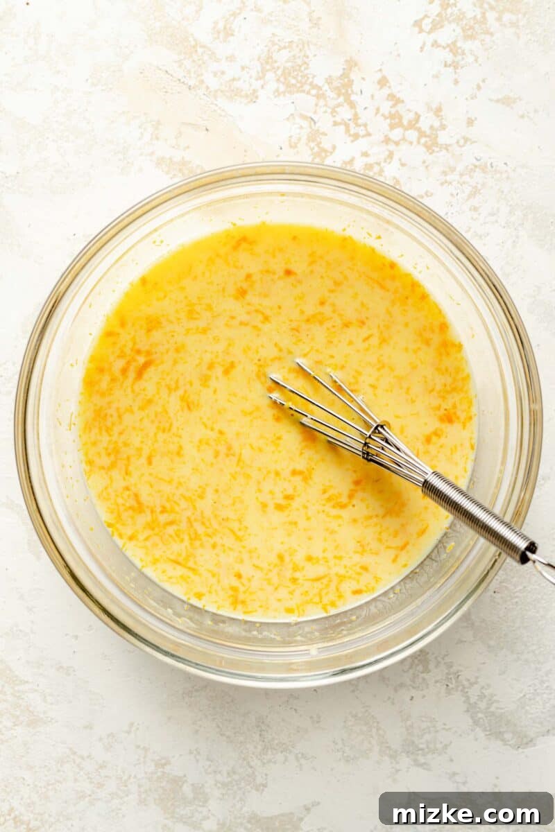 Combine the buttermilk, fresh orange zest, and vibrant orange juice to create the fragrant wet base for your pound cake. A bowl containing a mixture of creamy buttermilk, vibrant orange zest, and freshly squeezed orange juice, representing the fragrant wet ingredients for the orange pound cake batter.