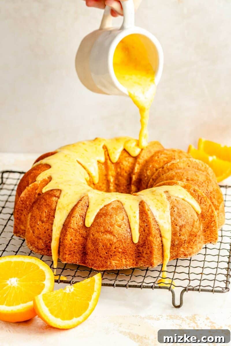 Drizzle the sweet orange glaze over the tender, buttery orange pound cake, completing this delightful and visually appealing dessert. Thick, glossy orange glaze being poured generously over the perfectly cooled orange pound cake, creating beautiful drips down the sides.