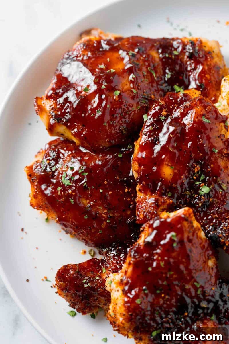 baked bbq chicken thighs with bbq sauce on a white plate