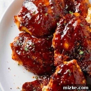 baked bbq chicken thighs with bbq sauce on a white plate
