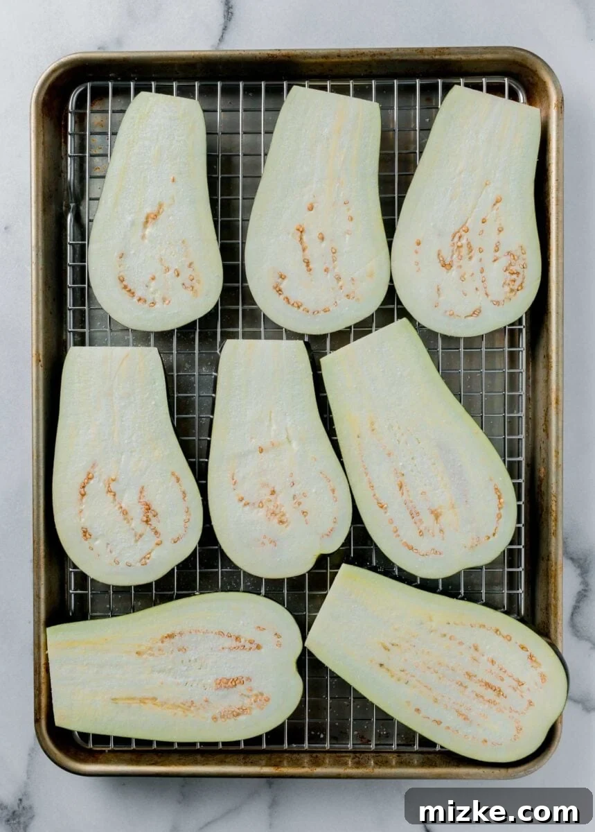 Golden Eggplant Spirals 4 Eggplant slices are arranged neatly on a wire rack over a baking sheet, ready for the crucial salting and pre-baking steps.