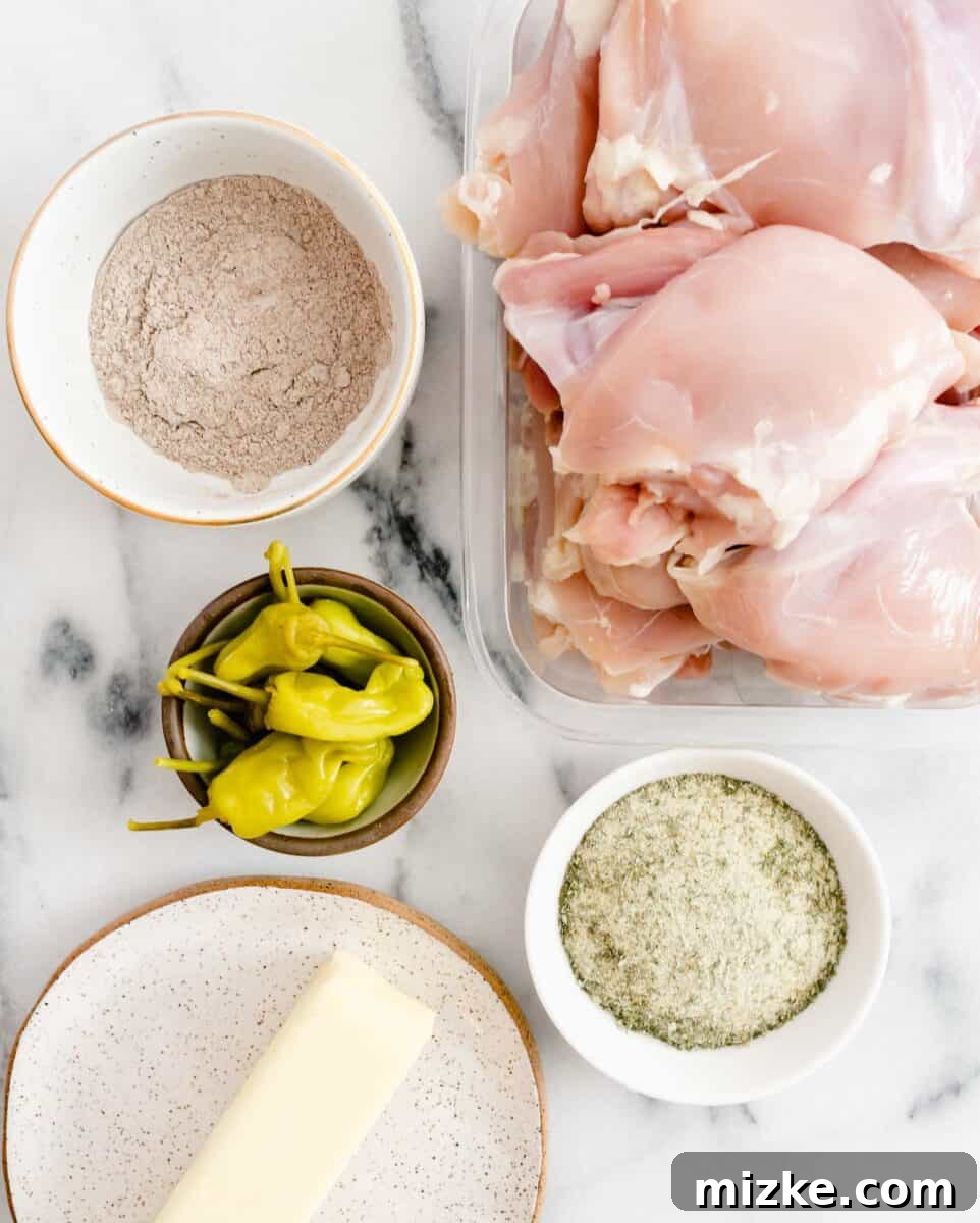 Zesty Mississippi Chicken 4 A simple yet powerful collection of ingredients for Mississippi chicken, including chicken thighs, seasoning packets, butter, and pepperoncinis