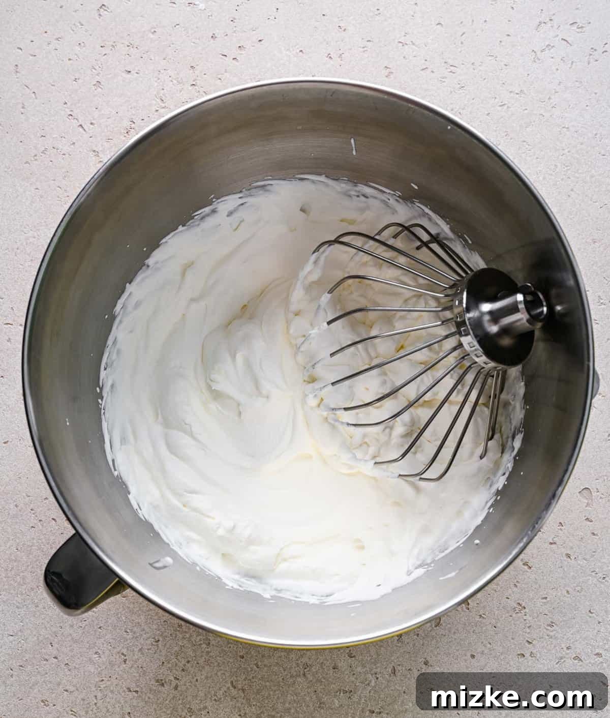 Whipped heavy cream forming stiff peaks. Freshly whipped cream, forming stiff peaks, shown in a clean mixing bowl.