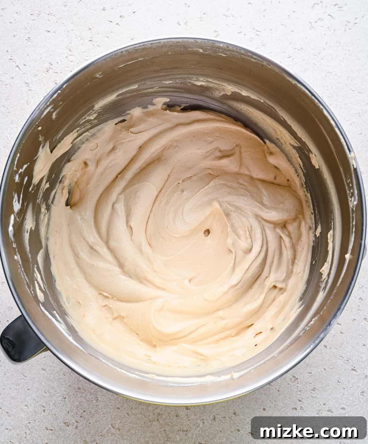 Folding whipped cream into the Biscoff ice cream base. The fluffy whipped cream being gently folded into the prepared Biscoff and condensed milk mixture.