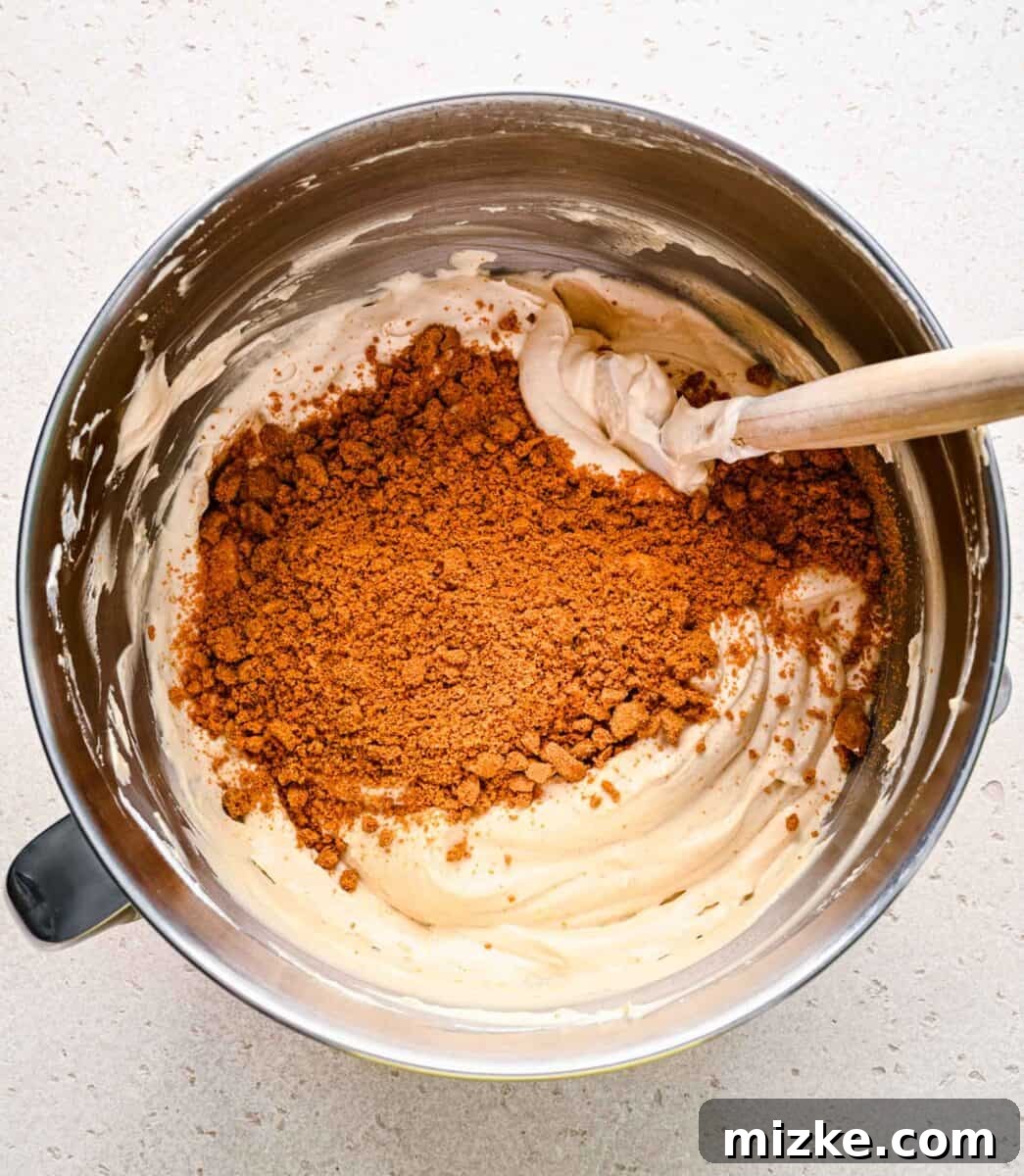Adding crunchy Biscoff cookies to the ice cream. Crushed Biscoff cookie crumbs being carefully folded into the almost-complete no-churn ice cream mixture.