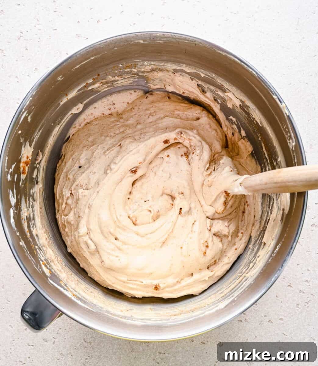 Biscoff ice cream ready for the freezer. The fully mixed no-churn Biscoff ice cream, with cookie crumbs visible, sitting in a large mixing bowl, ready for freezing.