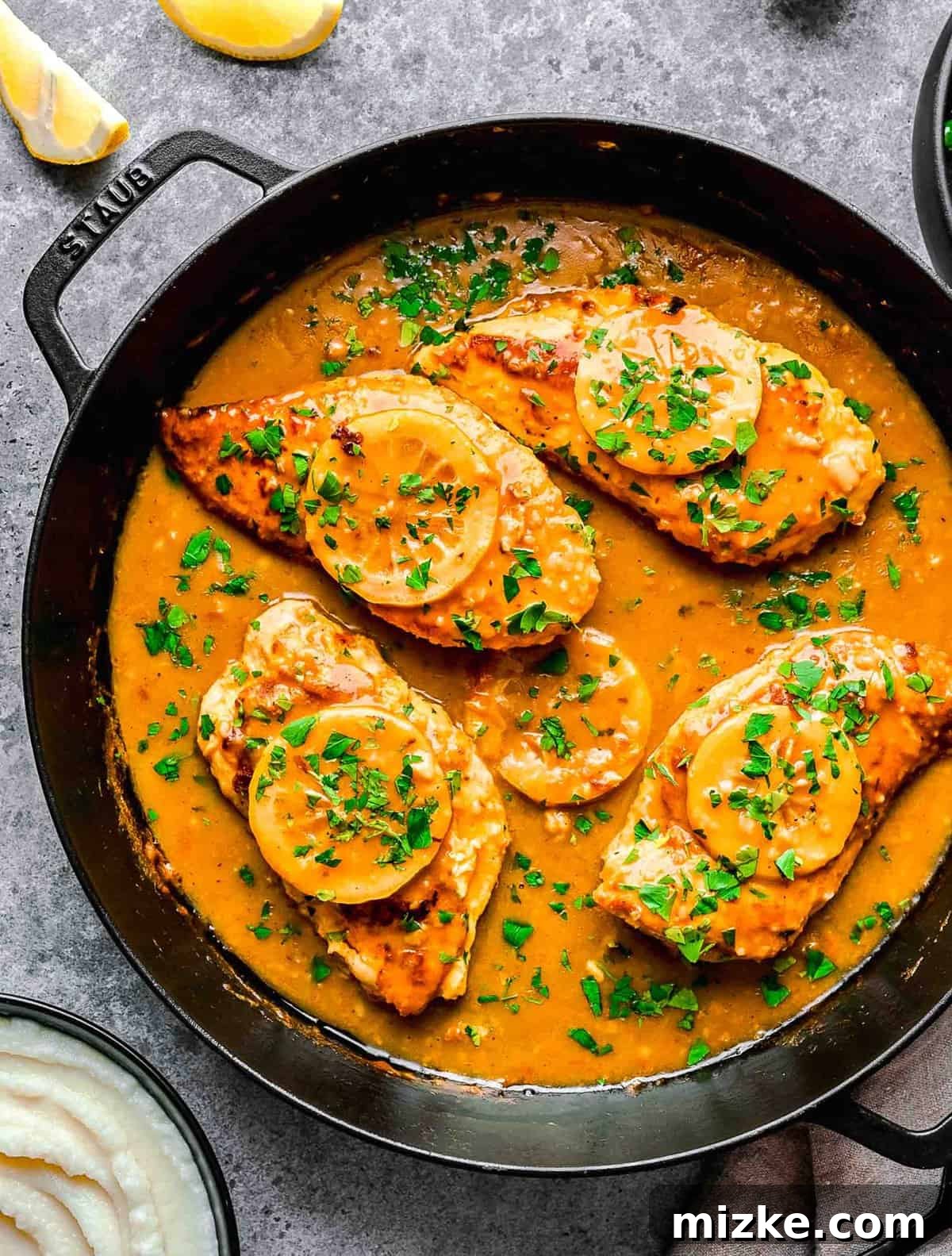 This easy chicken francese is made of tender chicken breast halves lightly breaded, pan-fried, and finished in a bright lemon-butter sauce. Overhead image of chicken francese in a pan.