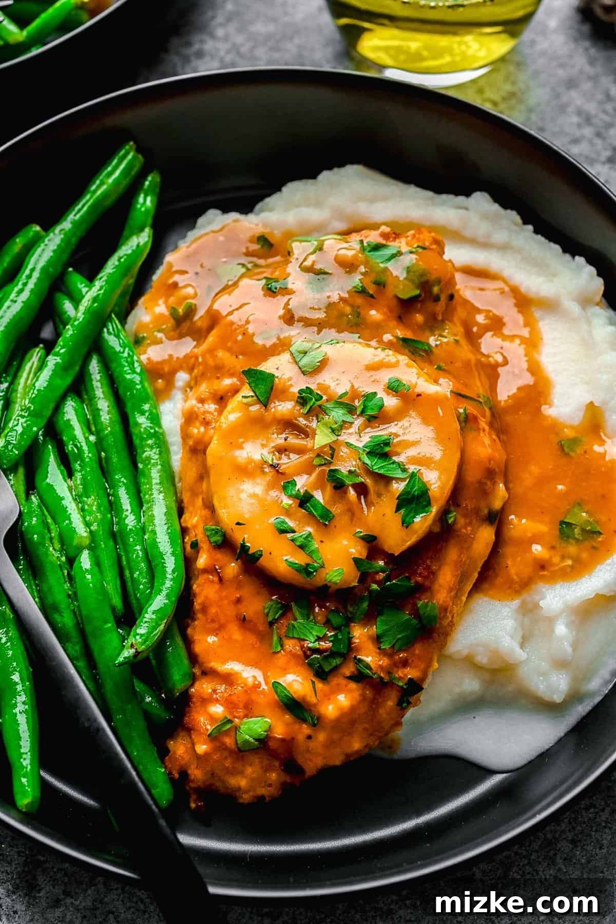 This easy chicken francese is made of tender chicken breast halves lightly breaded, pan-fried, and finished in a bright lemon-butter sauce. Overhead of chicken francese served on a plate over mashed potatoes with green beans.
