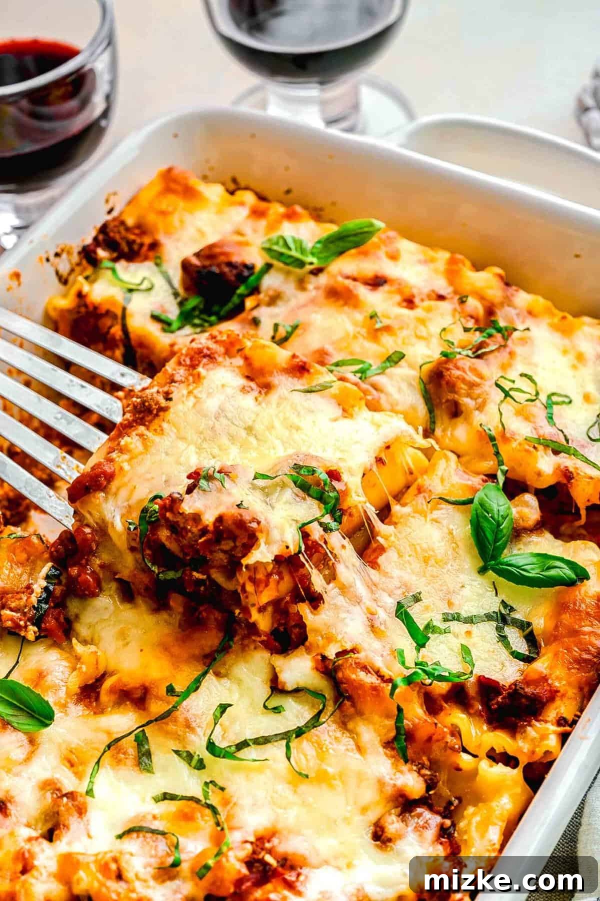 Serving a perfectly baked lasagna roll up with a spatula. An overhead shot of a spatula carefully lifting a single lasagna roll up from a baking pan, showcasing its golden cheese topping and rich sauce.