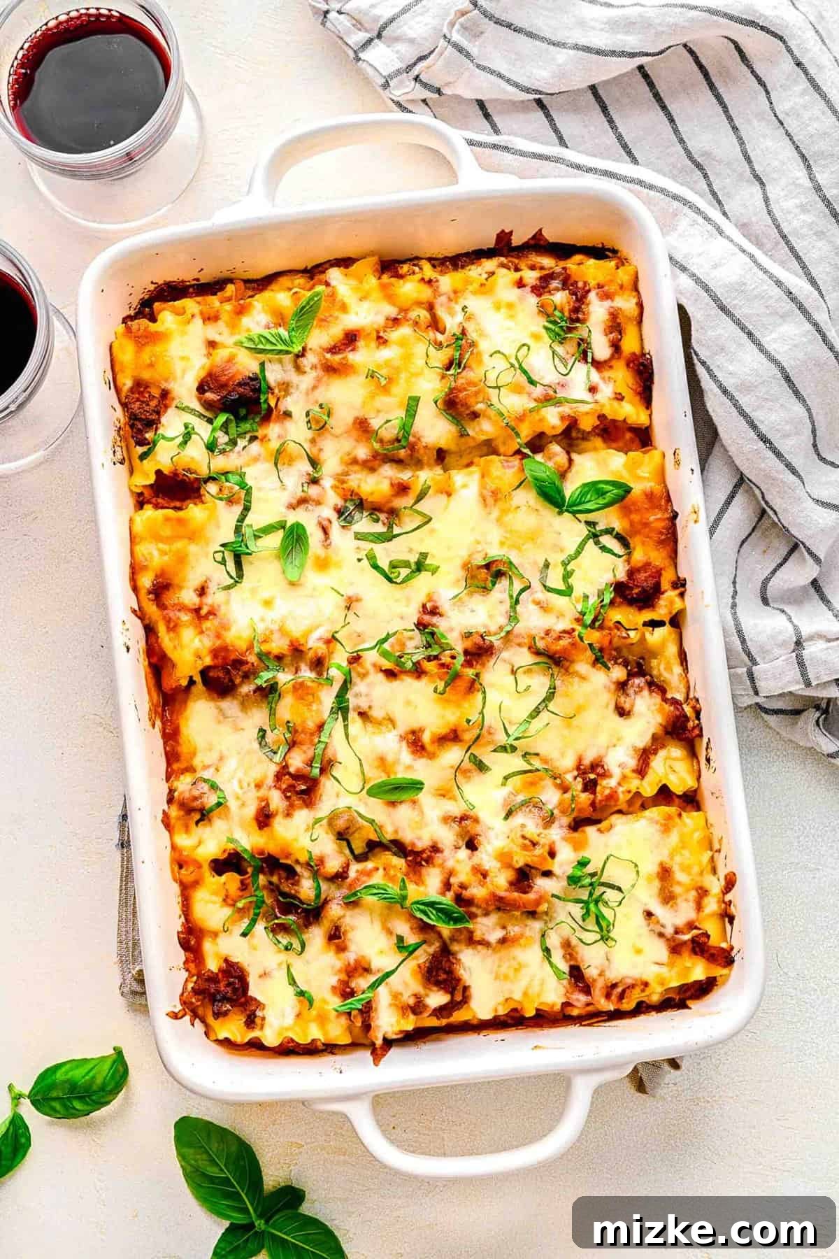 Lasagna roll ups are perfectly baked, offering a single-serve delight. Overhead view of several golden-brown lasagna roll ups nestled in a baking pan, covered in rich sauce and melted cheese.