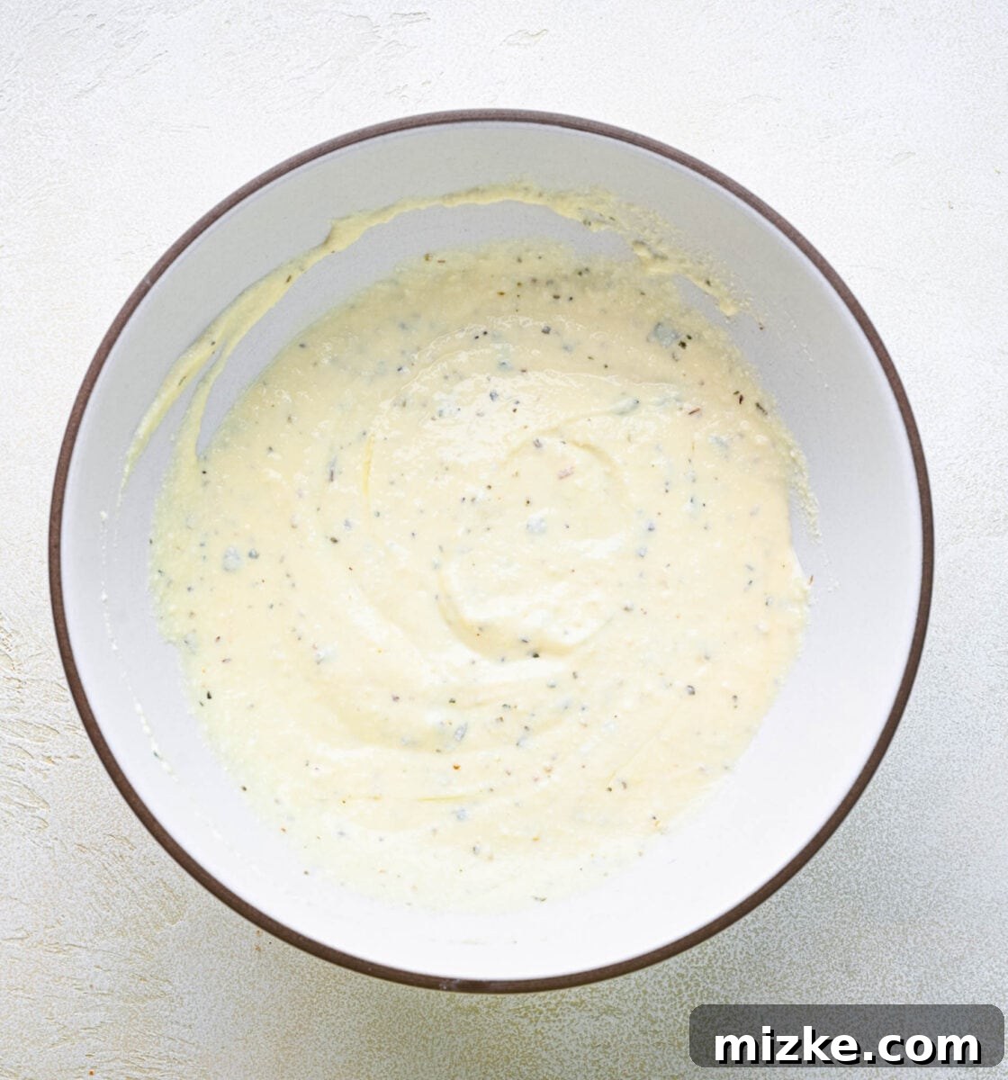Smooth and creamy ricotta filling, seasoned and ready for assembly. A bowl of creamy, white ricotta filling for lasagna rolls, perfectly mixed and ready to use.