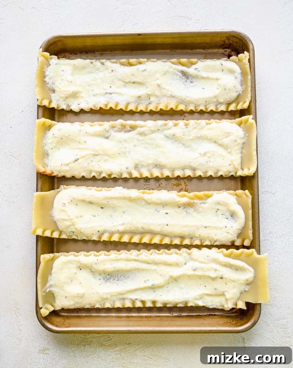 Spreading creamy ricotta filling onto a cooked lasagna noodle. A cooked lasagna noodle being spread with a layer of creamy ricotta filling on a cutting board.
