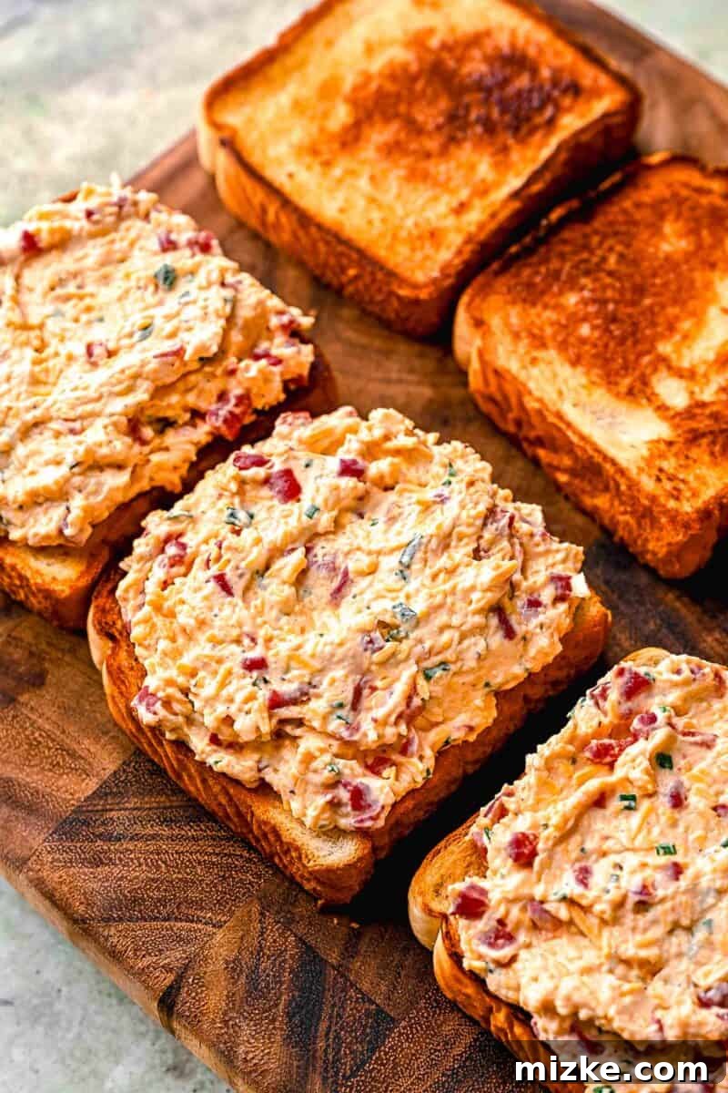 Southern Pimento Perfection 4 pimento cheese spread on slices of bread on a wood cutting board