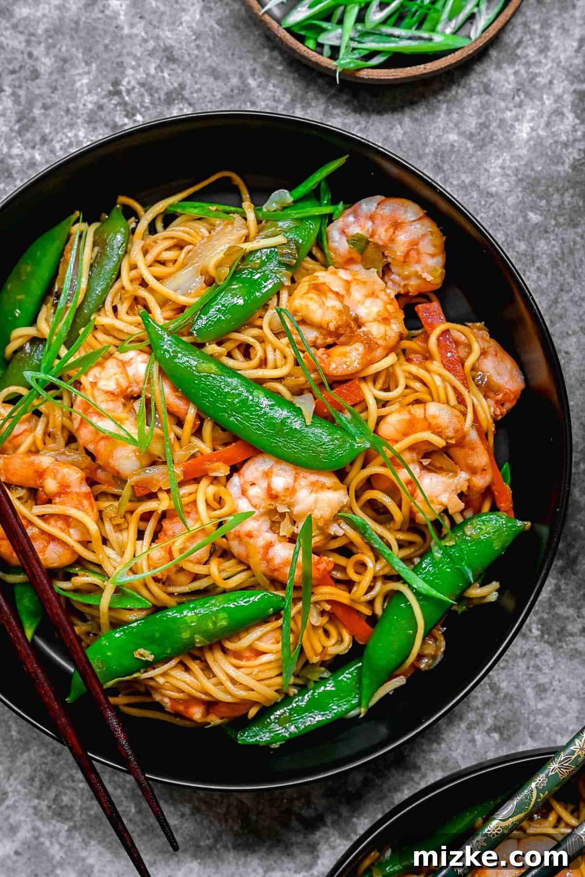 A close-up of delicious shrimp chow mein, featuring perfectly cooked shrimp, crisp vegetables, and savory noodles. Closeup of shrimp chow mein served in a bowl with chopsticks, highlighting the texture of the noodles and shrimp.