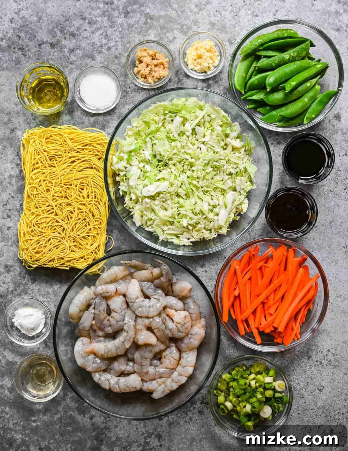 Fresh ingredients ready for delicious shrimp chow mein: noodles, shrimp, and various vegetables. Ingredients for homemade shrimp chow mein laid out on a table.