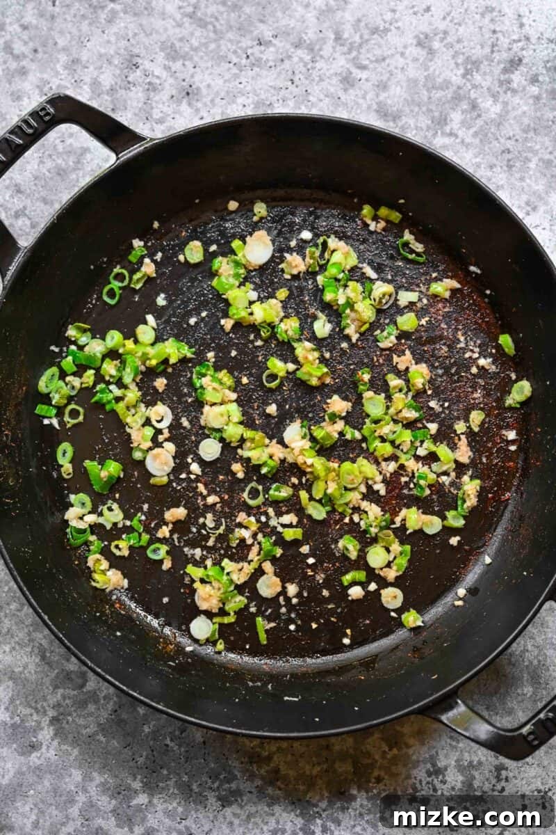 Infusing the oil with garlic, ginger, and scallion flavor. Sautéing aromatic garlic, ginger, and scallions in sesame oil.