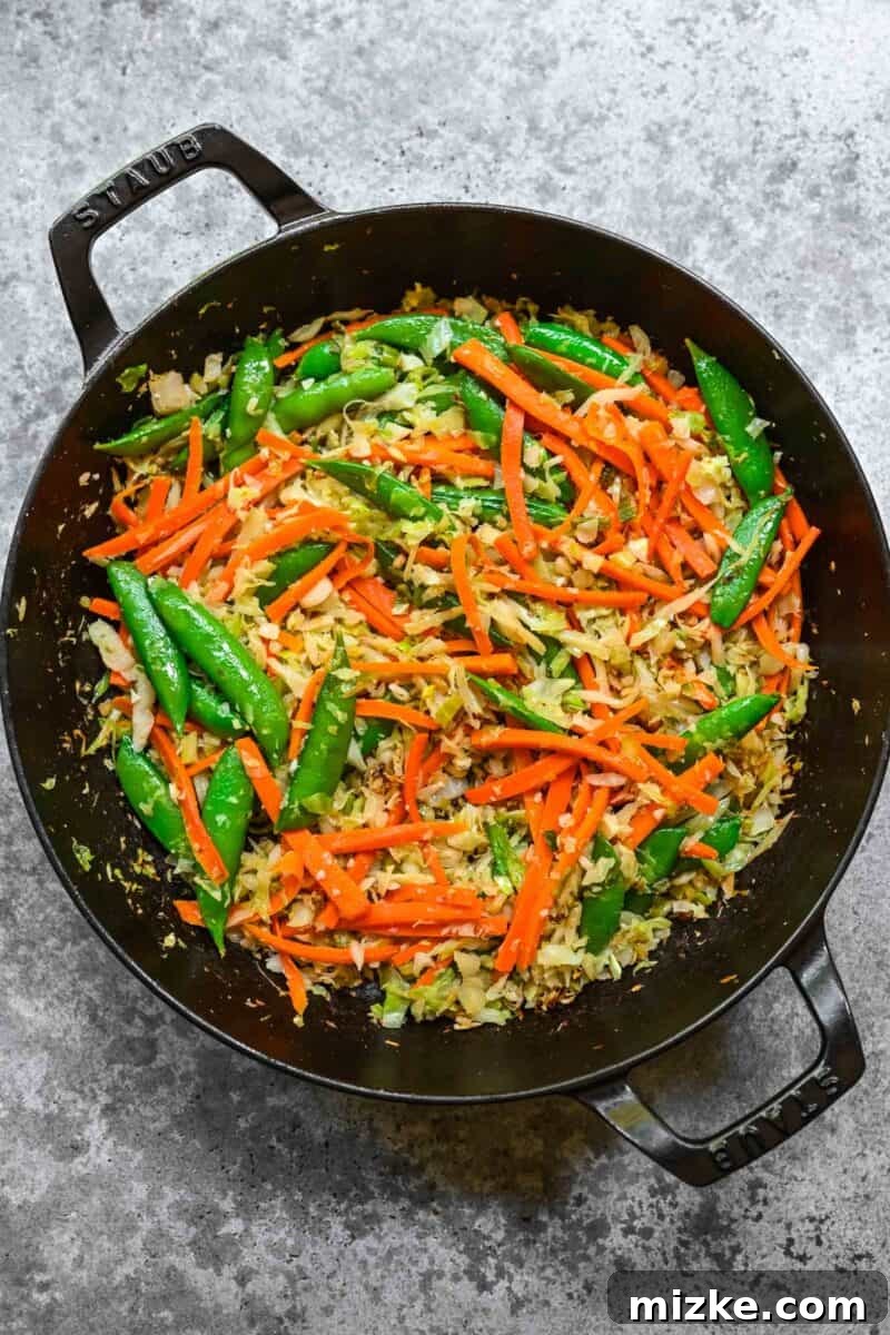 Adding crisp vegetables to the stir-fry for texture and nutrition. Stir-frying a colorful mix of fresh vegetables for chow mein.