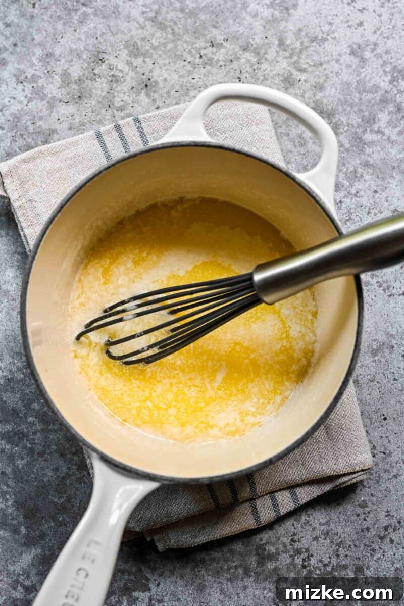 Whisking sugar into melted butter in a saucepan.