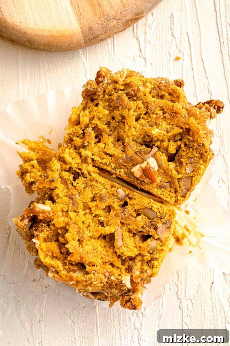 Cozy Pumpkin Pecan Muffins 5 pumpkin pecan muffin sliced in half to see interior dotted with chopped pecans