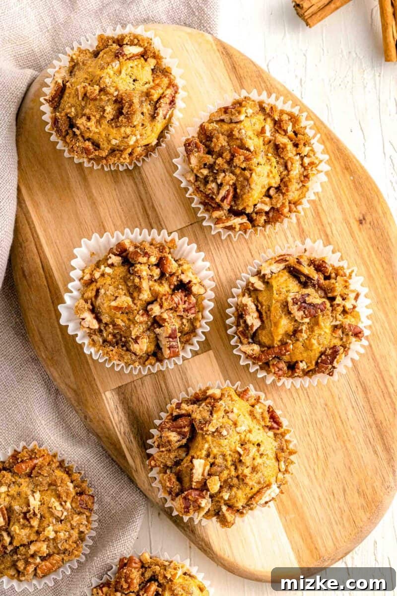 Cozy Pumpkin Pecan Muffins 6 pumpkin pecan muffins on top of a wooden cutting board