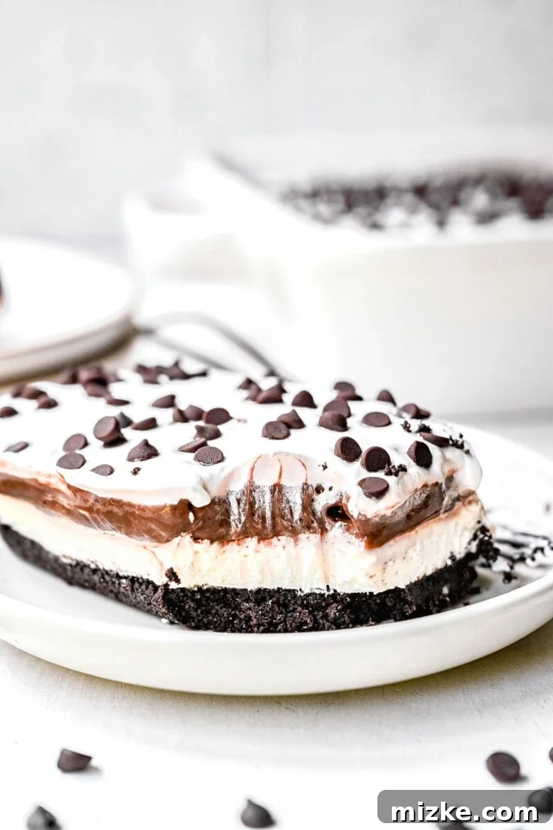 No-Bake Chocolate Dream 5 A fork taking a bite out of a corner of chocolate lasagna on a white plate