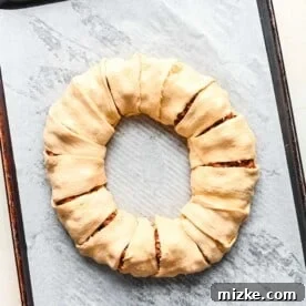 Crescent dough triangles carefully tucked and sealed around the seasoned ground beef filling, forming a complete taco ring before baking.