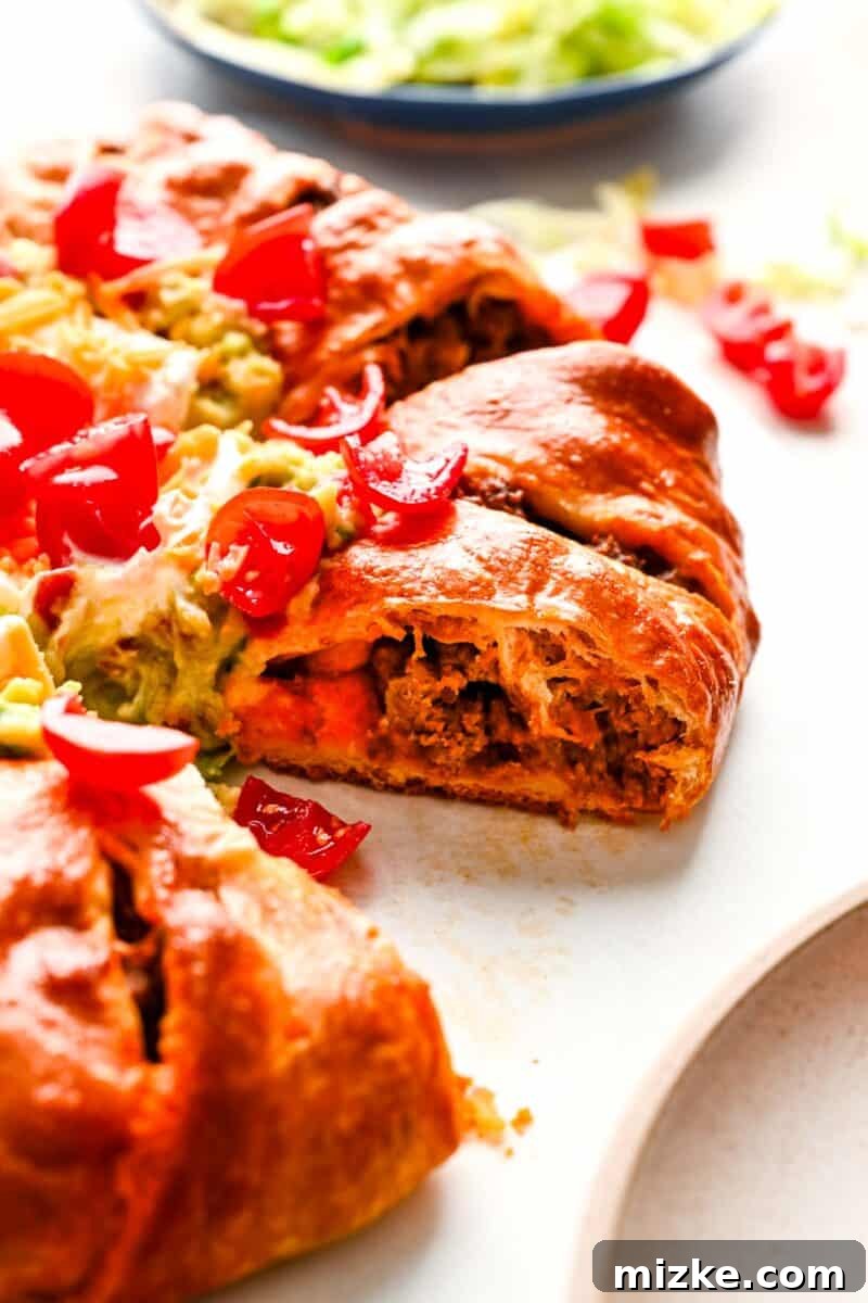 A close-up view of a baked taco ring slice, showcasing the savory ground beef and melted cheese filling encased in golden crescent dough.