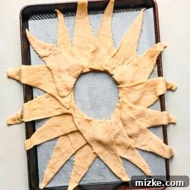 Crescent dough triangles arranged in a perfect ring on a baking sheet lined with parchment paper, forming the base of the taco ring.