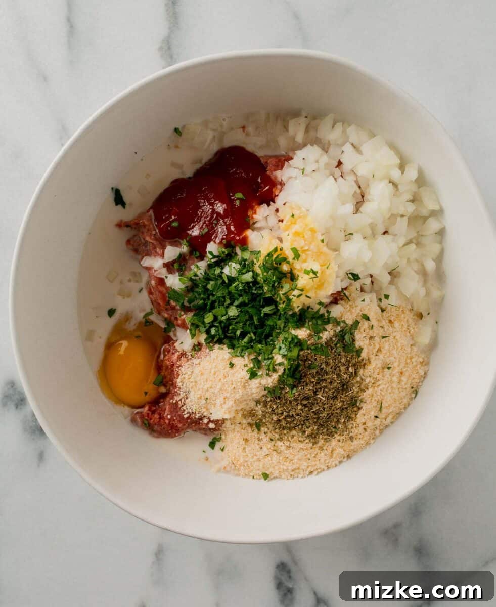 All the raw ingredients for air fryer meatloaf mixed together in a large white bowl.