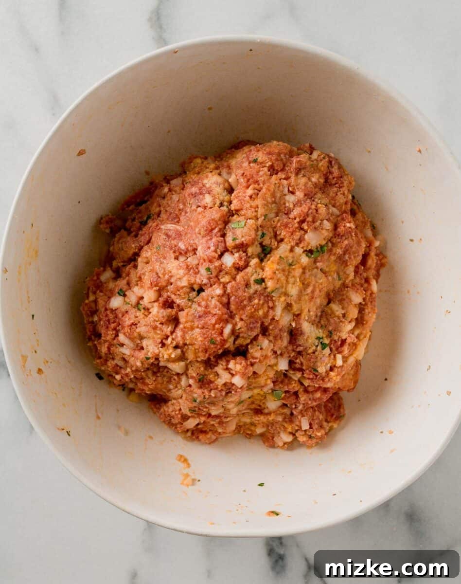 The meatloaf mixture expertly formed into a large, uniform ball in a pristine white mixing bowl.