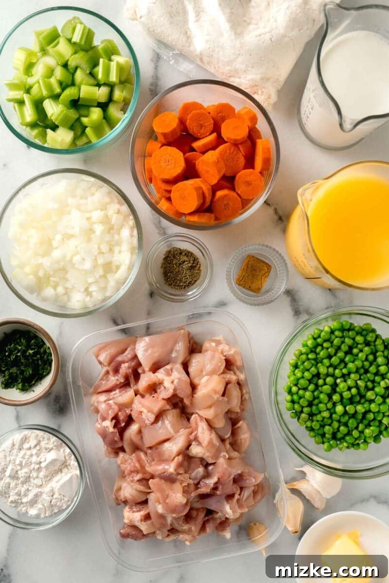 Hearty Stovetop Chicken and Dumplings with Biscuits 4 Various fresh ingredients laid out, including chicken thighs, carrots, celery, onion, garlic, peas, and a box of biscuit mix, ready for chicken and dumplings with biscuits.