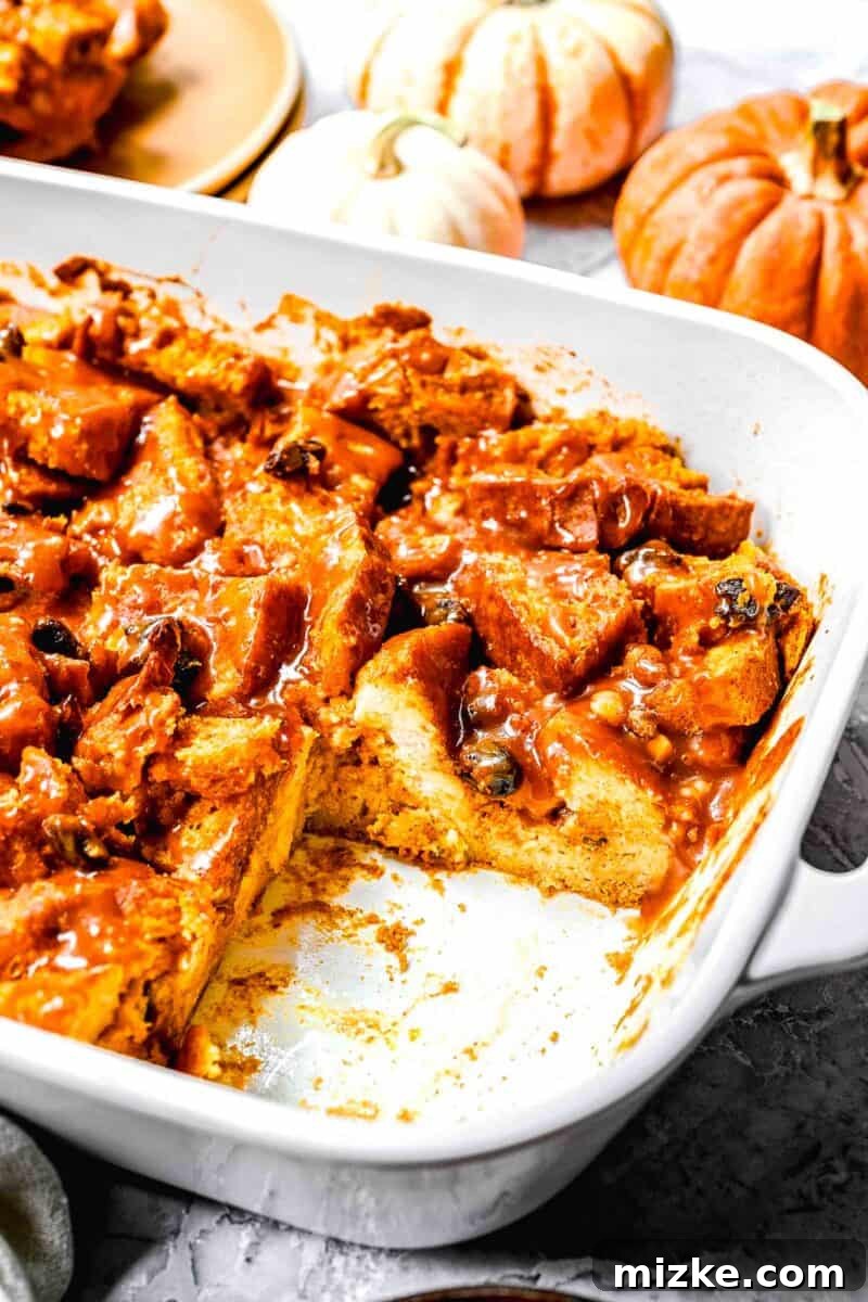 Close-up shot of the interior of a baked pumpkin bread pudding, showing its tender, custardy texture and golden-brown top, nestled in a white casserole dish.