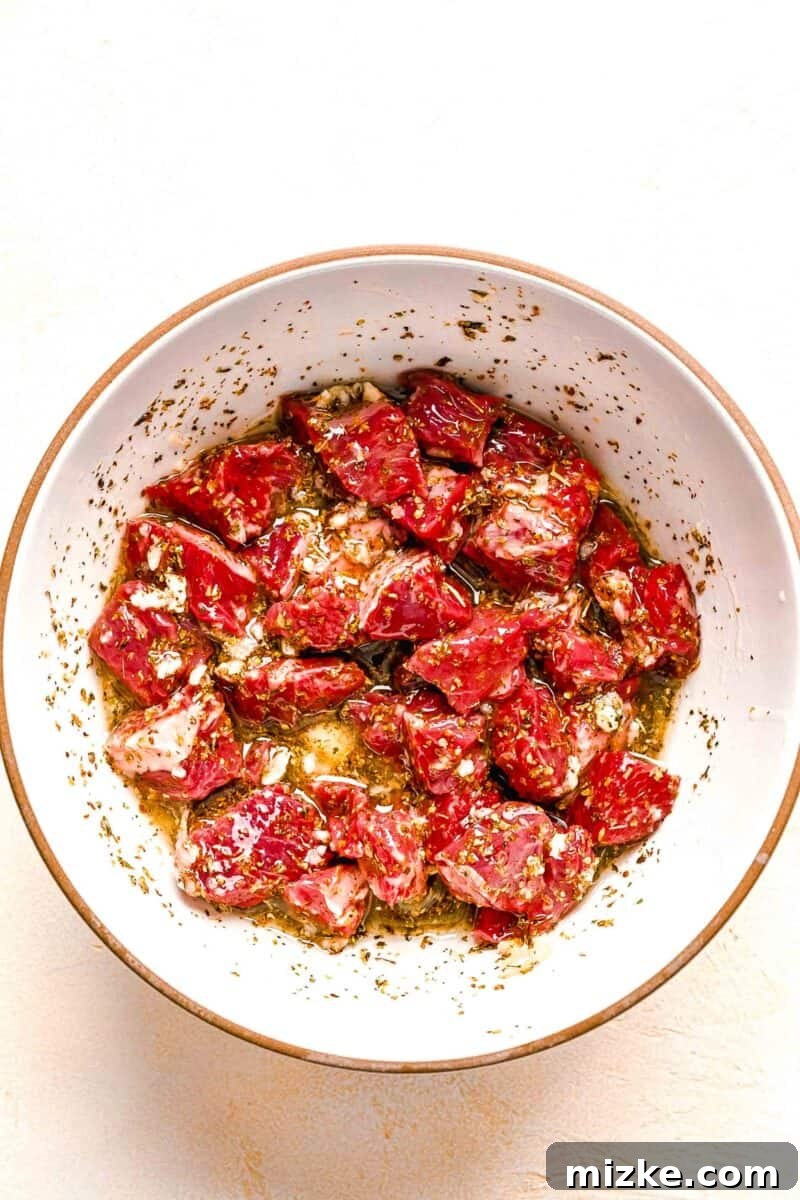 Beef cubes tossed in the Greek marinade, ensuring every piece is thoroughly coated for maximum flavor absorption.