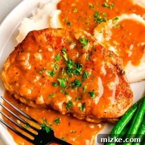 Perfectly Tender Instant Pot Pork Chops 11 Instant Pot Pork Chops next to mashed potatoes and green beans with pan drippings made into a gravy on top