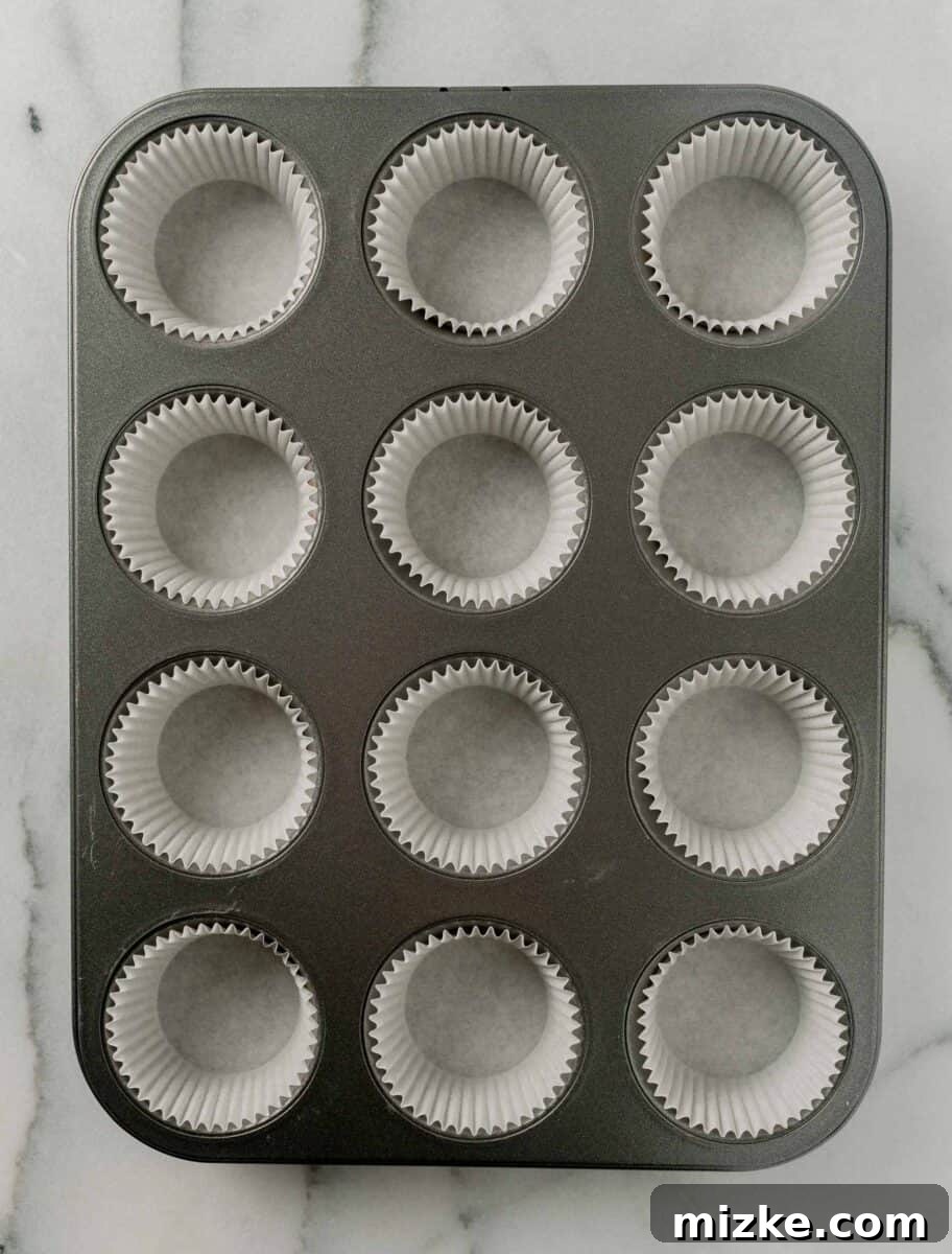 The perfect Fall baking treat, these pumpkin banana muffins are bouncy, tender, and oh-so-moist. You will absolutely fall in love with these! A standard 12-well metal muffin pan is neatly lined with paper muffin cups, prepared for filling with batter.