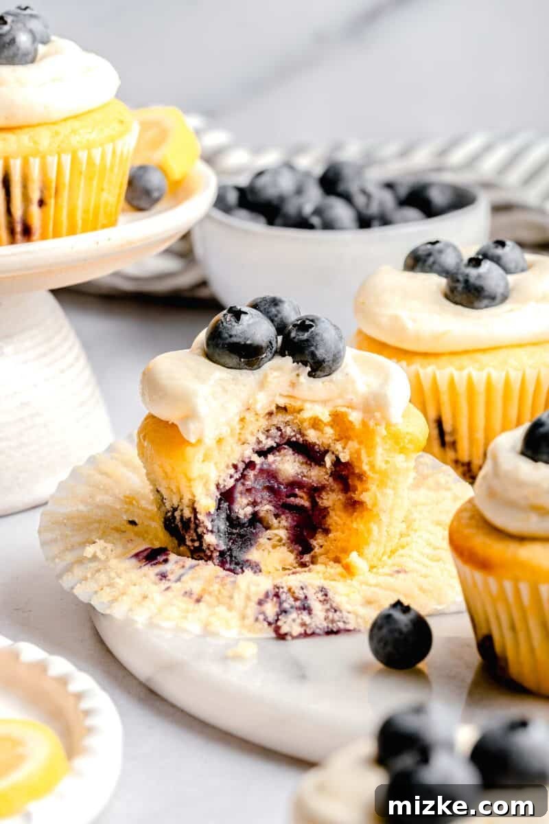 the inside of a lemon blueberry cupcake after it has been bitten into. it shows the cupcake bursting with fresh blueberries