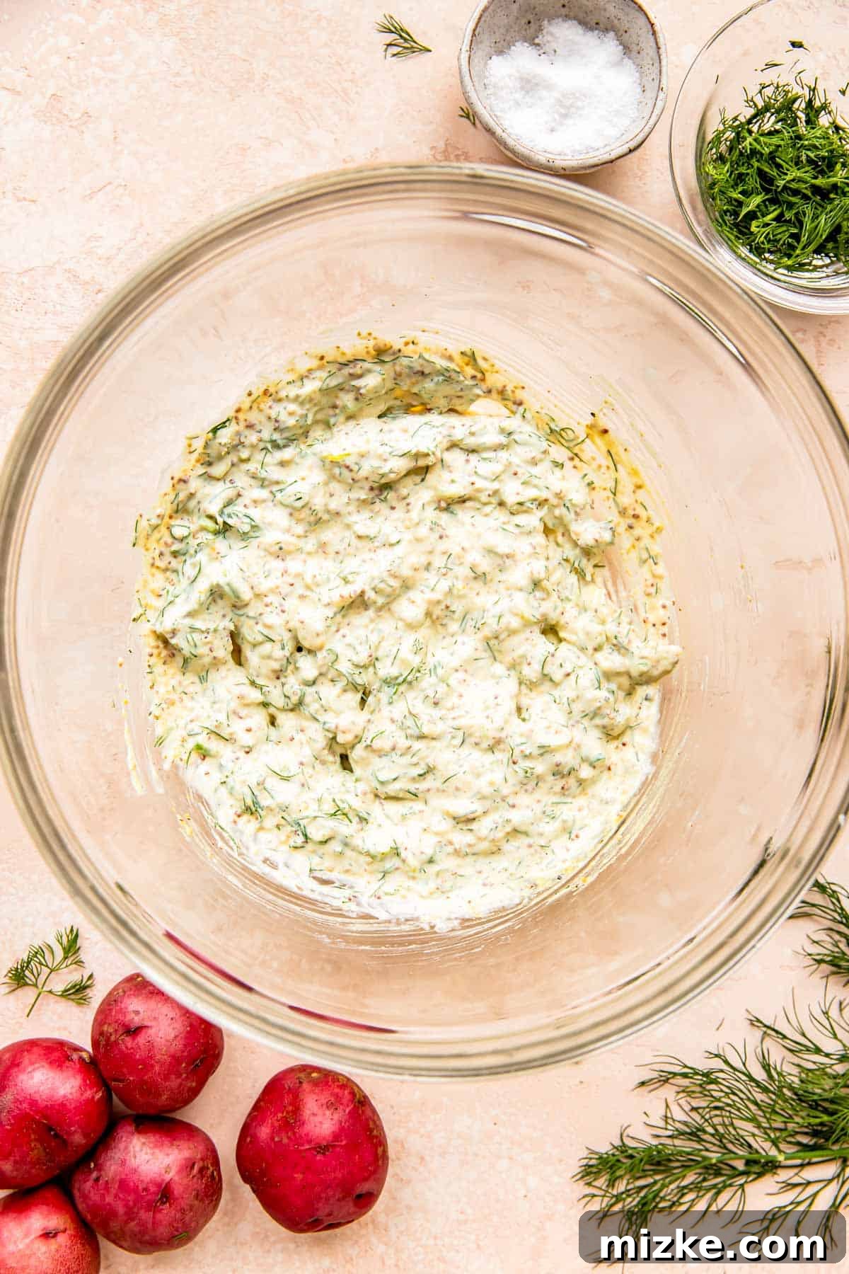 Zesty Dill Potato Salad 5 The creamy dill potato salad dressing, featuring Greek yogurt and fresh herbs, has been thoroughly mixed until smooth and ready.